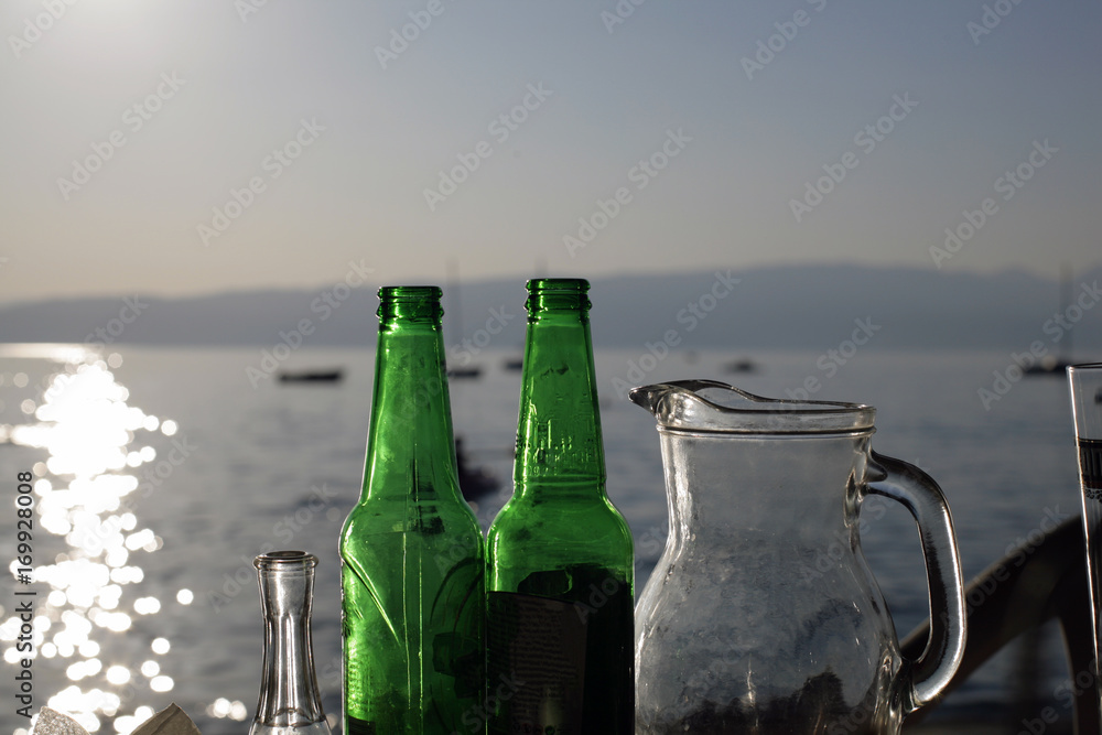 Close up empty bottles of beer and glasses on the beach sunset; drinks and summer concept. Close up empty bottles of beer and glasses on the beach sunset; drinks and summer concept.