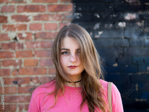 portrait of a modern trendy girl teenager on the background of old vintage brick wall and black wall. © pavelkant