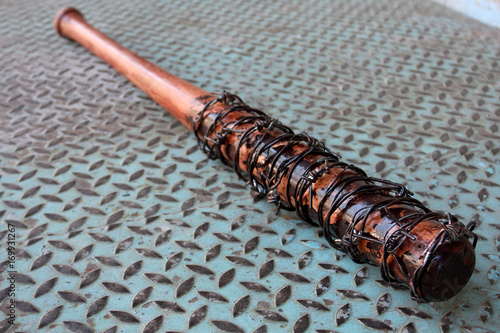 baseball bat with barbed wire on rusty blue metal sheet
