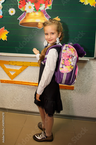 Little girl with colorful backpack posing against turquoise wall. School concept. Back to School. Celebrating the end of another successful school year photo