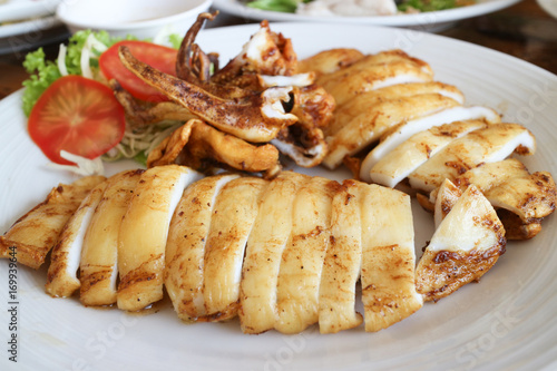 grilled squid on white dish with vegetables