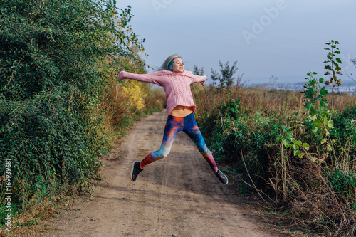 Portrait of a young woman jumping on the autumn road
