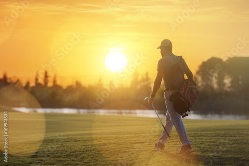 handsome middle eastern golfer carrying bag and walking to next hole photo