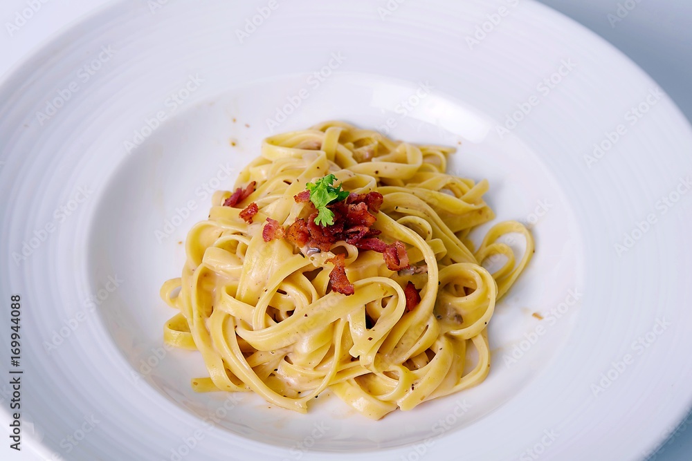 closeup spaghetti carbonara on white plate with bacon 