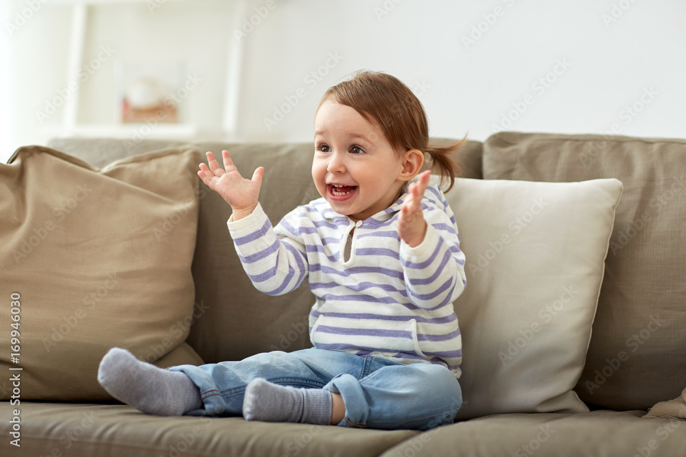 happy smiling baby girl sitting on sofa at home happy smiling baby girl sitting on sofa at home