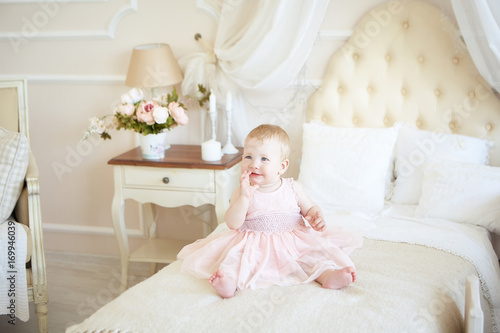 smiling little baby girl in pink dress on the bed