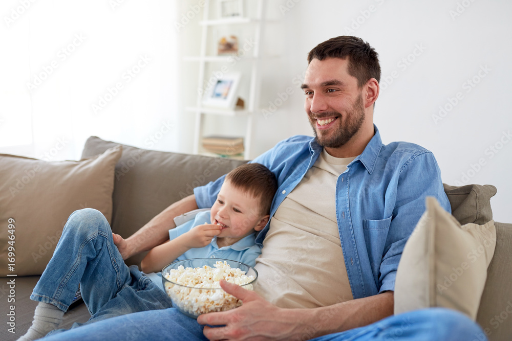 father and son with popcorn watching tv at home father and son with popcorn watching tv at home