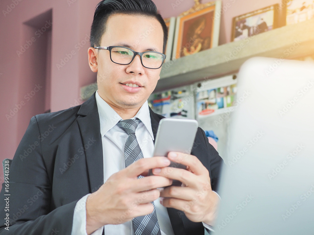 Focus Close up Portrait of happy Asia businessman using phone while working on laptop Focus Close up Portrait of happy Asia businessman using phone while working on laptop