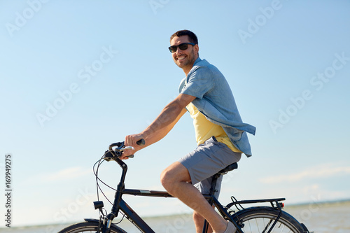 happy man riding bicycle along summer beach