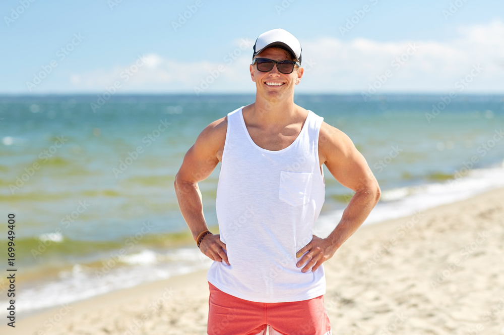 smiling young man in sunglasses on summer beach