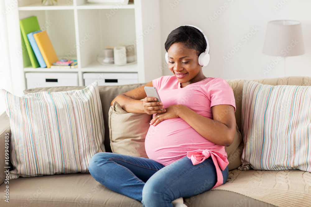 pregnant woman in headphones with smartphone pregnant woman in headphones with smartphone