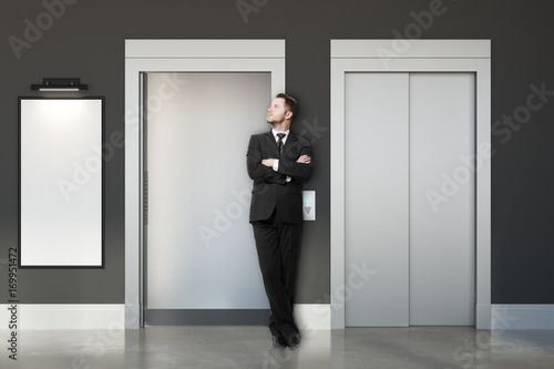 Thoughtful businessman with elevators and banner