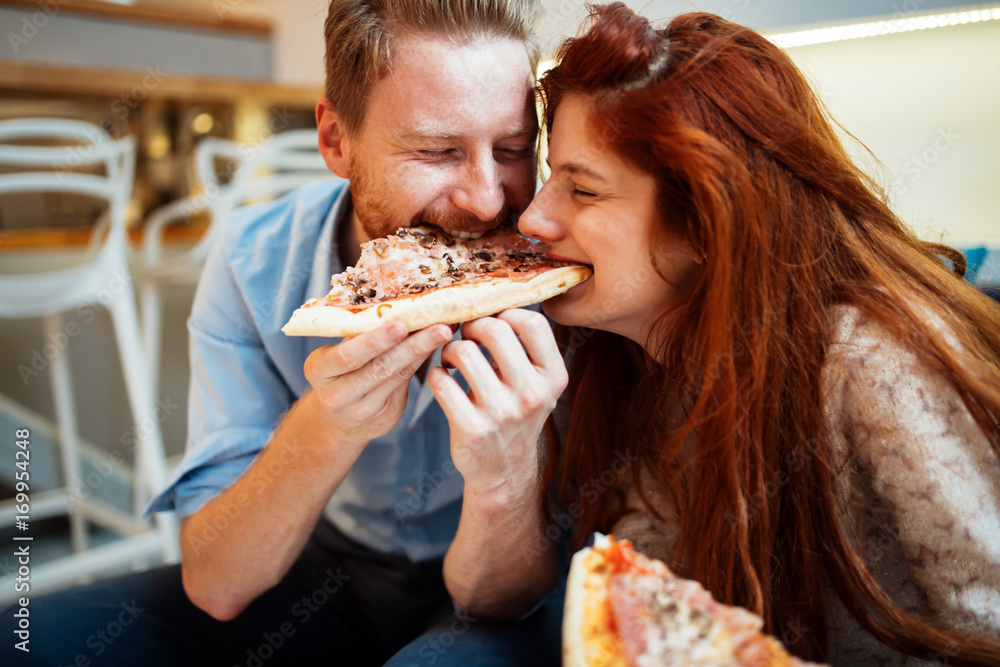 Couple sharing pizza and eating