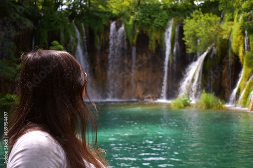 close up on beautiful woman looks on waterfall in forest 