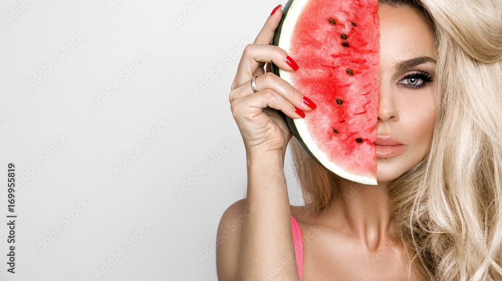 Obraz premium Beautiful, woman with long blonde hair, keeps the face watermelon , she have amazing eyes and beautiful face and full and sensual lips and flawless skin
