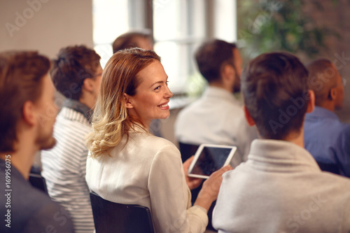 Profile of smiling woman in audience on lecture on company meeting