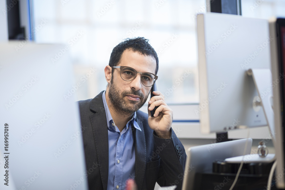 Manager con occhiali parla al telefono immerso nel lavoro del suo ufficio Manager con occhiali parla al telefono immerso nel lavoro del suo ufficio