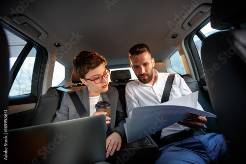 successful business couple working together in back seat of car.