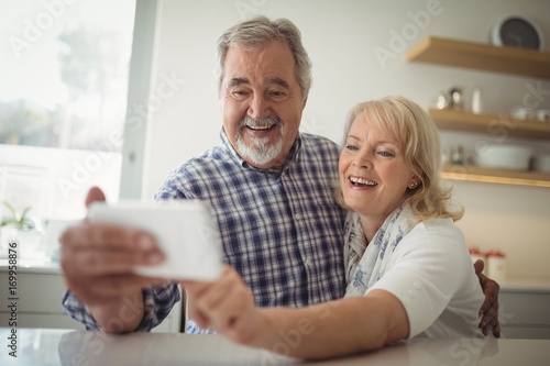 Senior couple taking a selfie in the kitchen