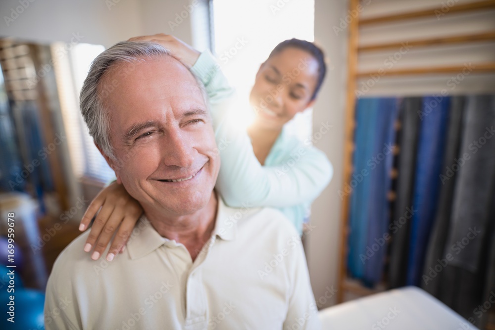 Fototapeta premium Smiling senior male patient receiving neck massage from female