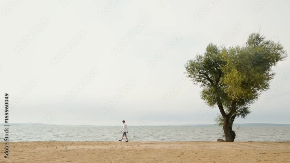 A man walks along the shore with skyline in the background. A man walks along the shore with skyline in the background.