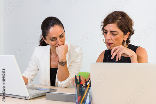 Mujeres de negocios observan atentas el contenido en una tablet. photo