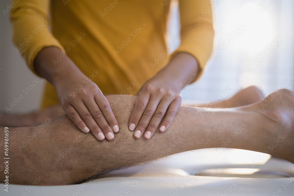 Midsection of female therapist massaging calf of male senior Midsection of female therapist massaging calf of male senior