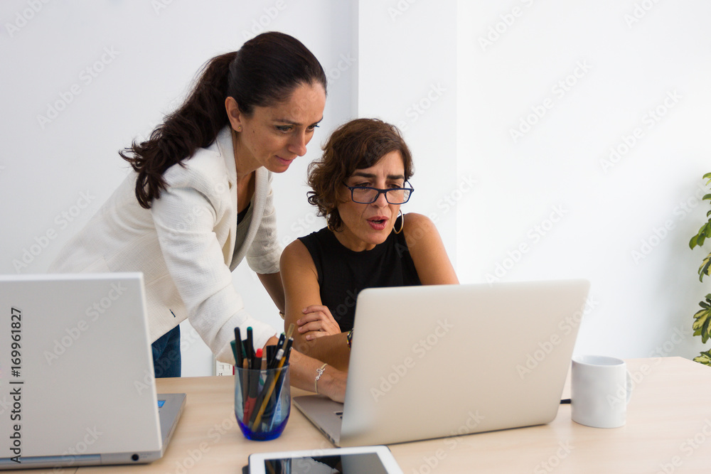 Mujeres de negocios conversan sobre el contenido en un ordenador.