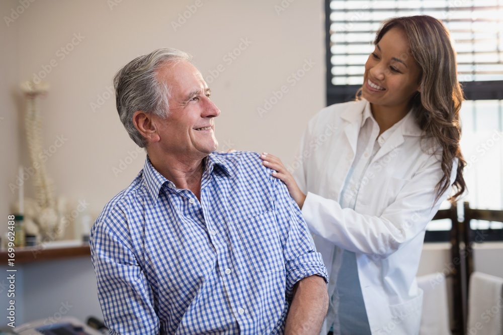 Smiling female therapist looking at male patient against window Smiling female therapist looking at male patient against window