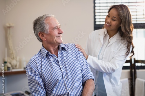Smiling female therapist looking at male patient against window
