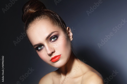 Young beautiful woman with orange lips and hair bun