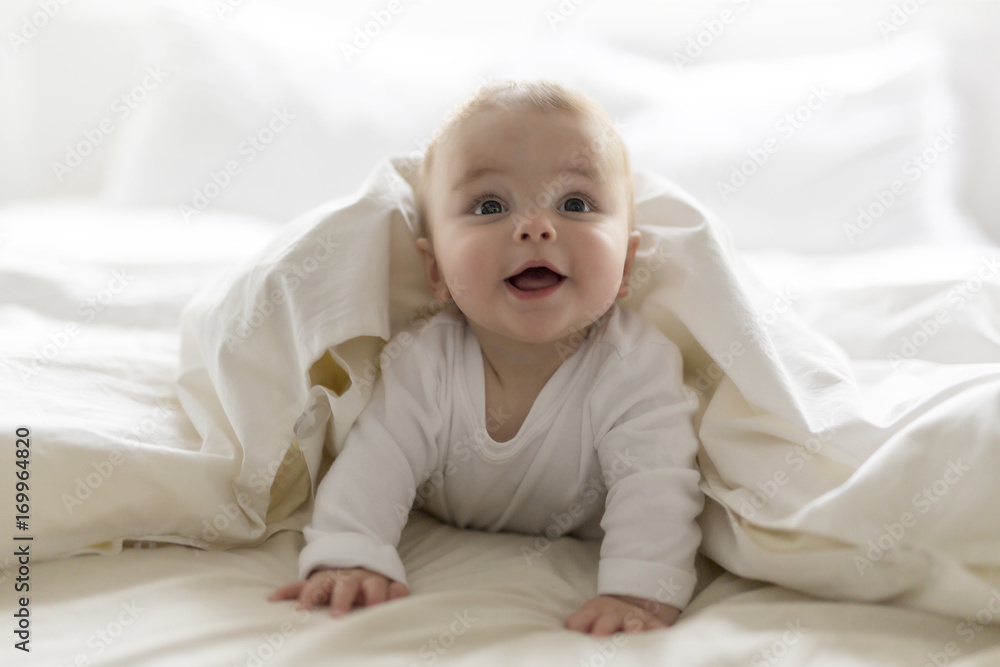 Cute happy 7 month baby girl in diaper lying and playing - obrazy, fototapety, plakaty 