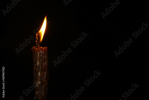 Flame of a lonely burning church wax candle isolated on a black background