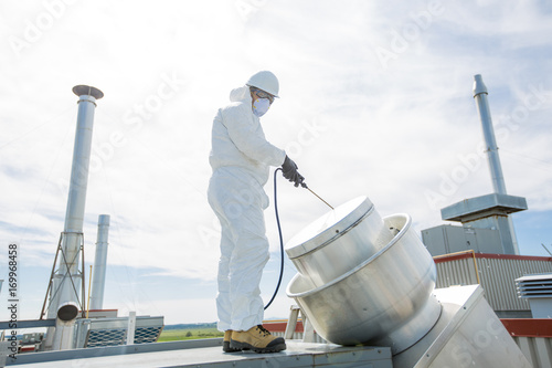 professional in protective uniform, mask, gloves in the roof for cleaning