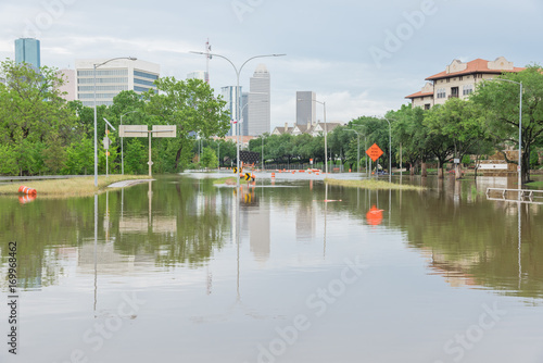 High water rising along Allen Parkway with road warning signs. Residential buildings and downtown Houston in background under storm cloud sky. Heavy rains from tropical storm caused many flooded areas photo