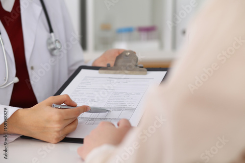 Close up of a female doctor pointing into an application form while consulting patient