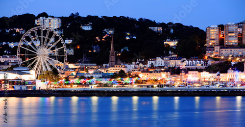 Torquay Promenade at dusk with illuminated lights and a ferris wheel overlooking the sea
