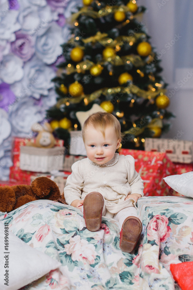 Lovely little baby girl playing in the winter on the floor near the Christmas tree on the Christmas holidays, studio shot. Lovely little baby girl playing in the winter on the floor near the Christmas tree on the Christmas holidays, studio shot.