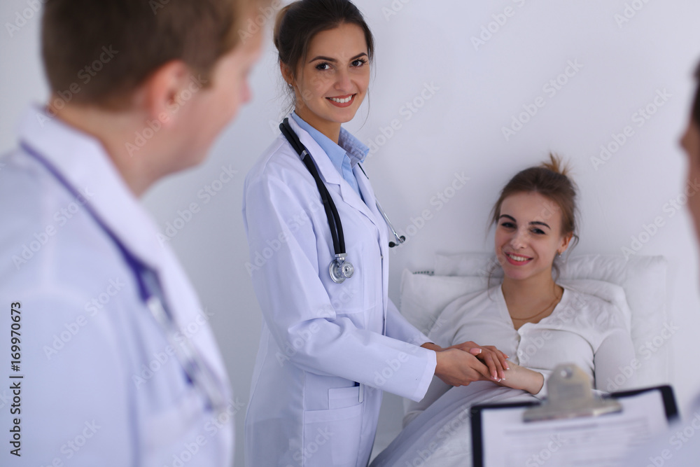 Female doctor smiling on the background with patient in the bed Female doctor smiling on the background with patient in the bed
