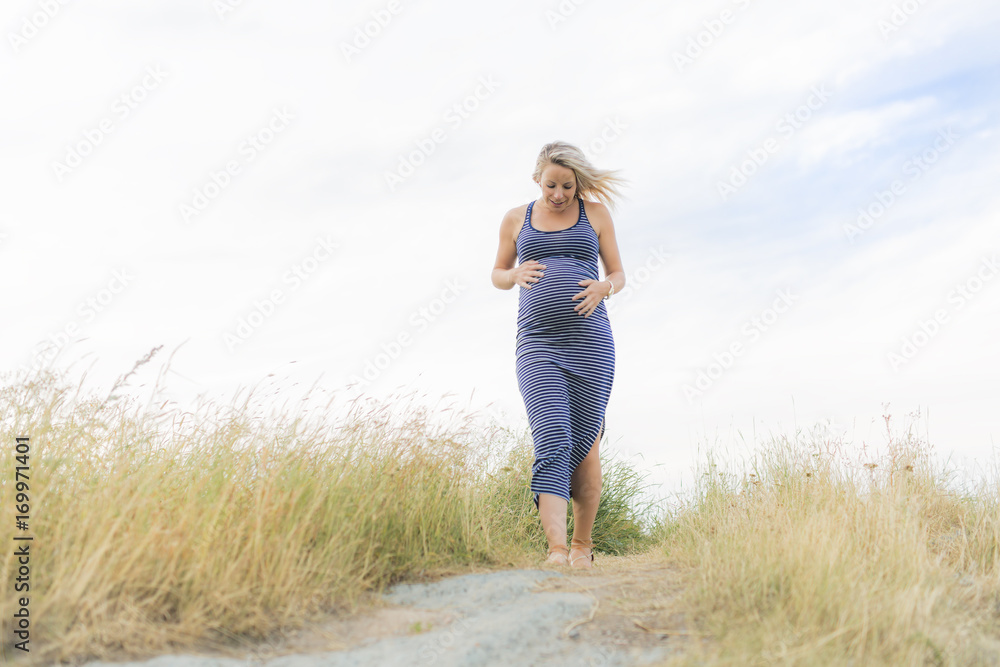 Portrait of a young beautiful blond pregnant woman on the side of the beach Portrait of a young beautiful blond pregnant woman on the side of the beach