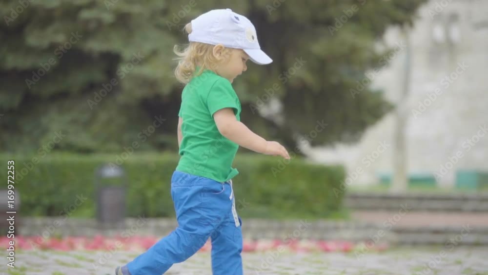 Little boy running along the city street , he passing by people. Little boy running along the city street , he passing by people.