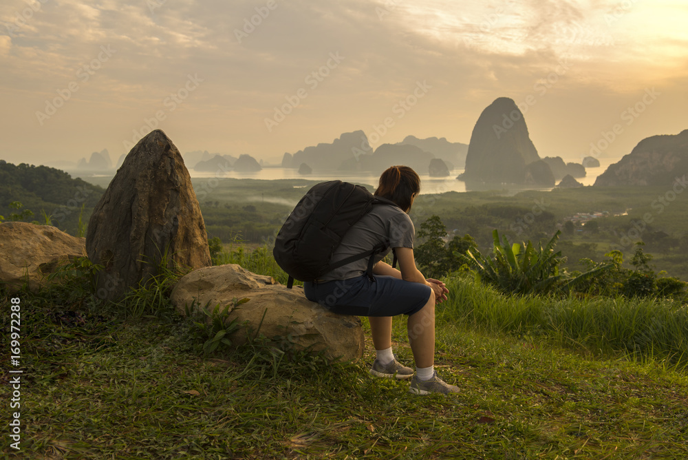 Asian lady with black bag sit on rock look at mountain and river view in morning