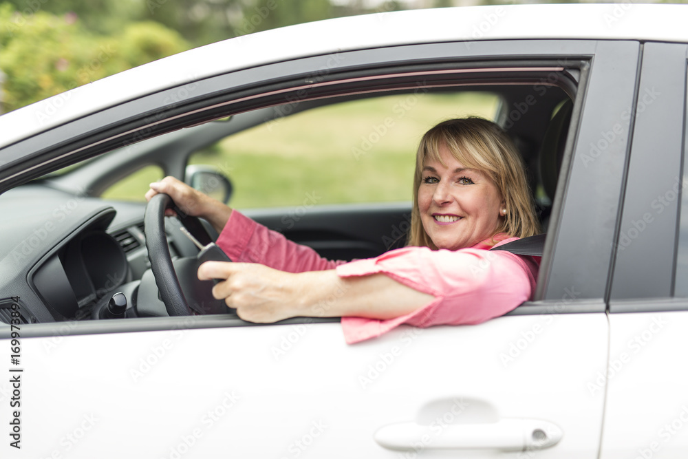 Happy and smiling senior woman in black car