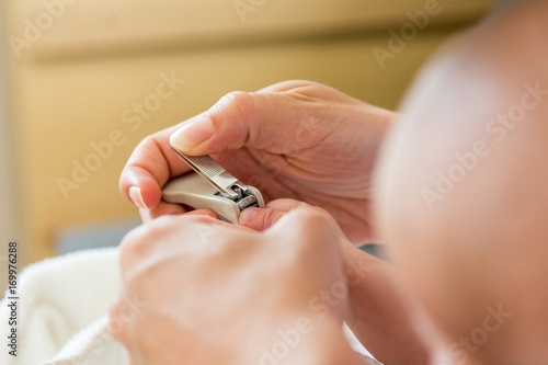 Mother gently cutting her baby nails.