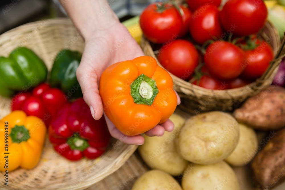 Woman holding fresh bell pepper at vegetable stall Woman holding fresh bell pepper at vegetable stall