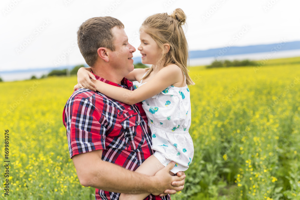 Happy family father and child daughter on yellow flowers on nature in summer Happy family father and child daughter on yellow flowers on nature in summer