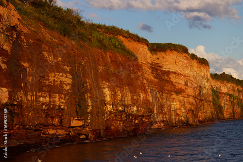 View of the red earth of Caplan's coastline in Quebec with blue sky