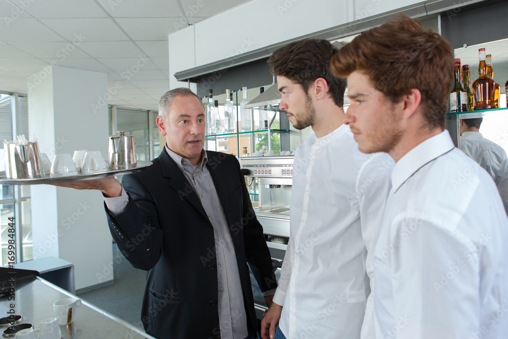 2 young waiters learning from experienced senior teacher