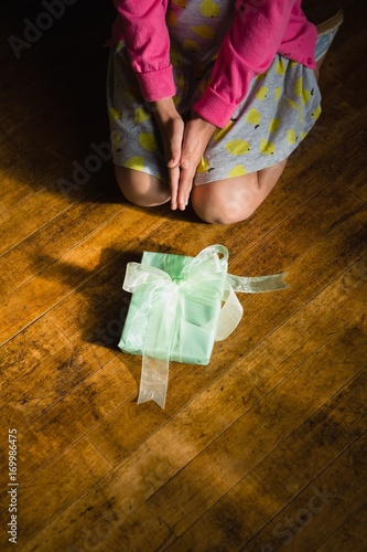 Girl sitting with gift box on wooden floor