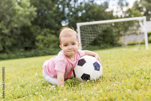 cute baby girl playing on grass with ball